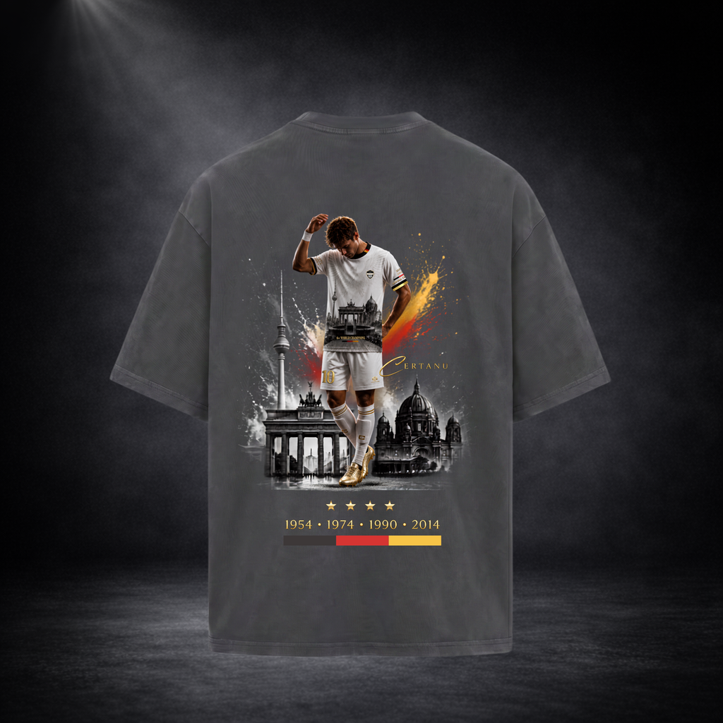 Rückansicht eines dunkelgrauen Oversized CERTANU T-Shirts vor einem hochwertigen dunklen Studiohintergrund mit weicher Spotlight-Beleuchtung. Das große Rückenmotiv zeigt einen Fußballspieler in weißem Trikot mit goldenen Schuhen vor ikonischen Berliner Wahrzeichen wie dem Brandenburger Tor, dem Berliner Fernsehturm und dem Berliner Dom. Dynamische Schwarz-Rot-Gold-Farbeffekte symbolisieren die deutschen Nationalfarben und verleihen dem Design eine moderne Streetwear-Optik. Unter dem Motiv befinden sich vier