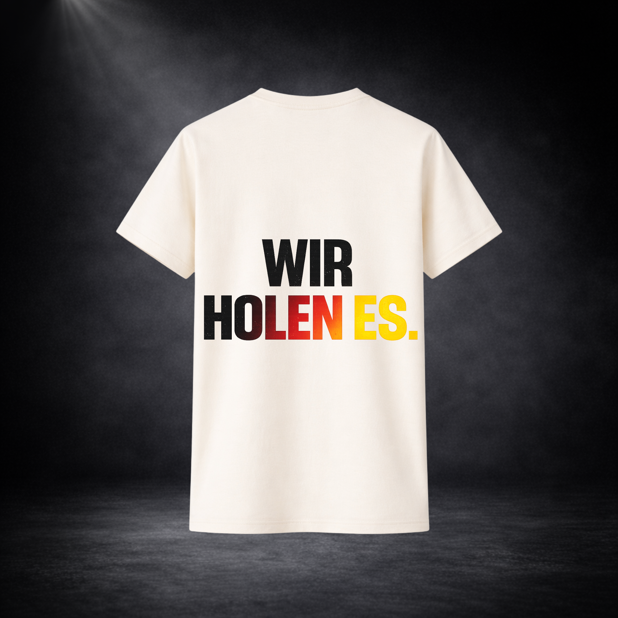 Rückseite eines beigen Deutschland Fan T-Shirts mit großem „WIR HOLEN ES.“ Schriftzug in Schwarz, Rot und Gelb, minimalistisches Fußball WM 2026 Design vor dunklem Studio Hintergrund