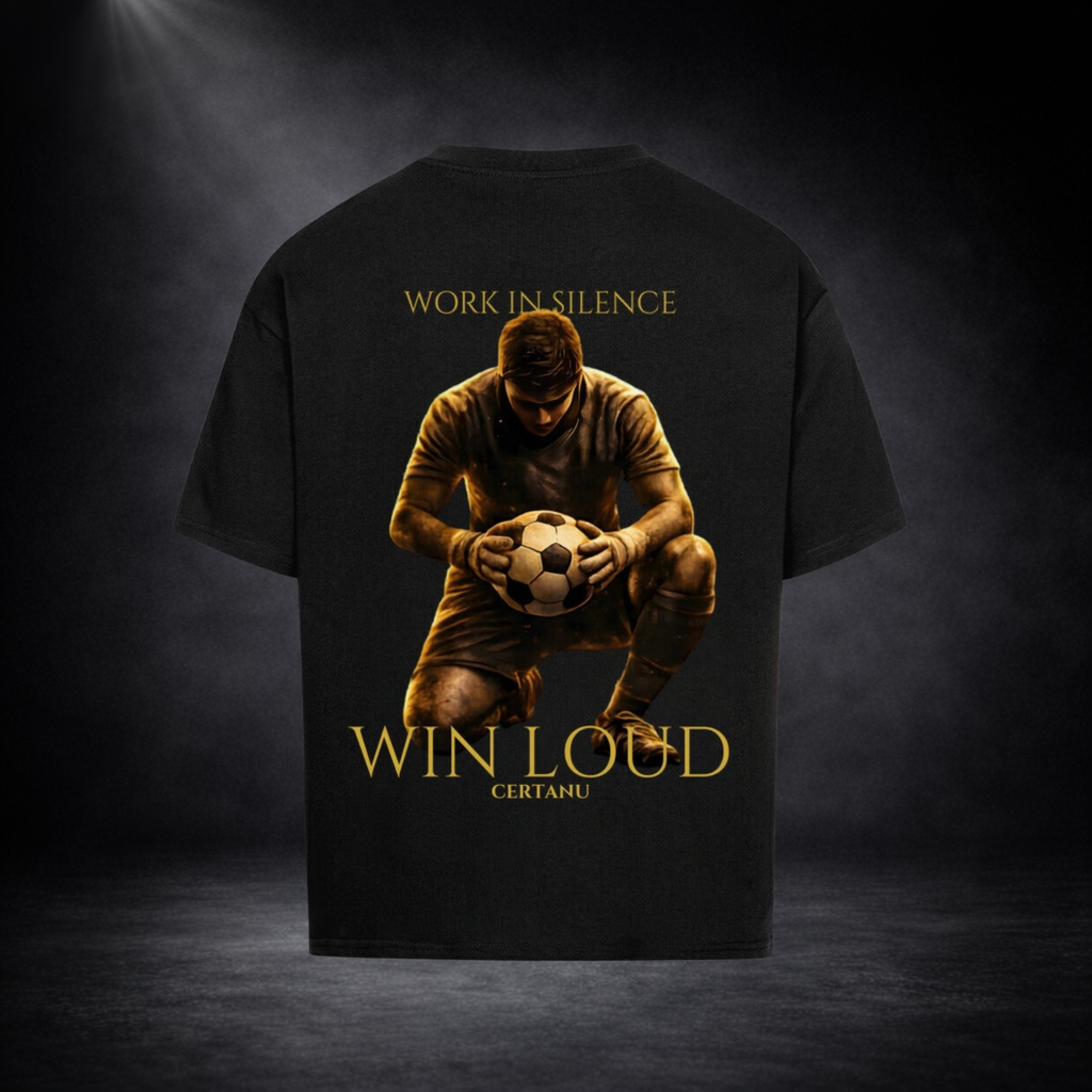 Schwarzes oversized T-Shirt in Rückansicht mit großem goldenem Motiv eines knienden Fußballspielers mit Ball, Schriftzug „WORK IN SILENCE“ oben und „WIN LOUD CERTANU“ unten, vor dunklem Studio-Hintergrund
