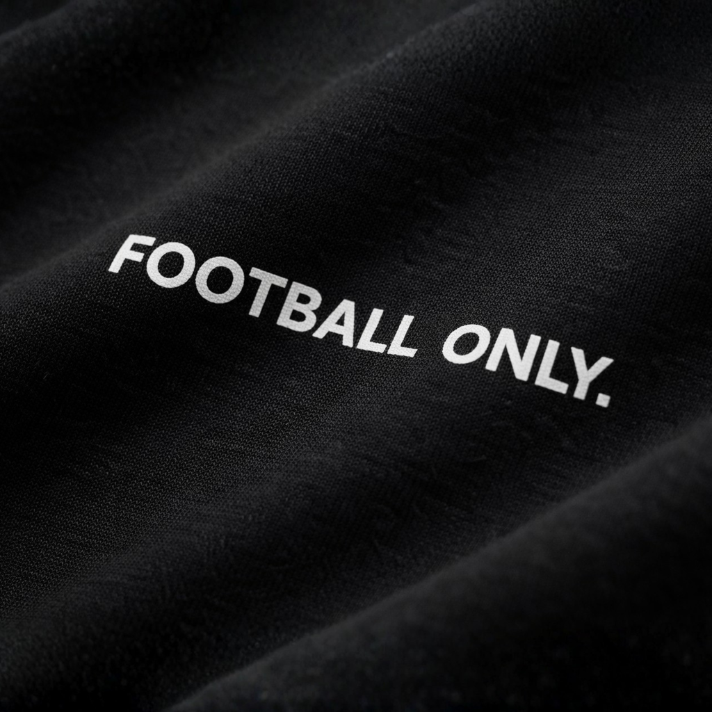 Detailaufnahme eines schwarzen T-Shirts mit weißem „Football Only“ Schriftzug, Fokus auf Stoffstruktur und Druckqualität, dunkler, edler Studio-Look