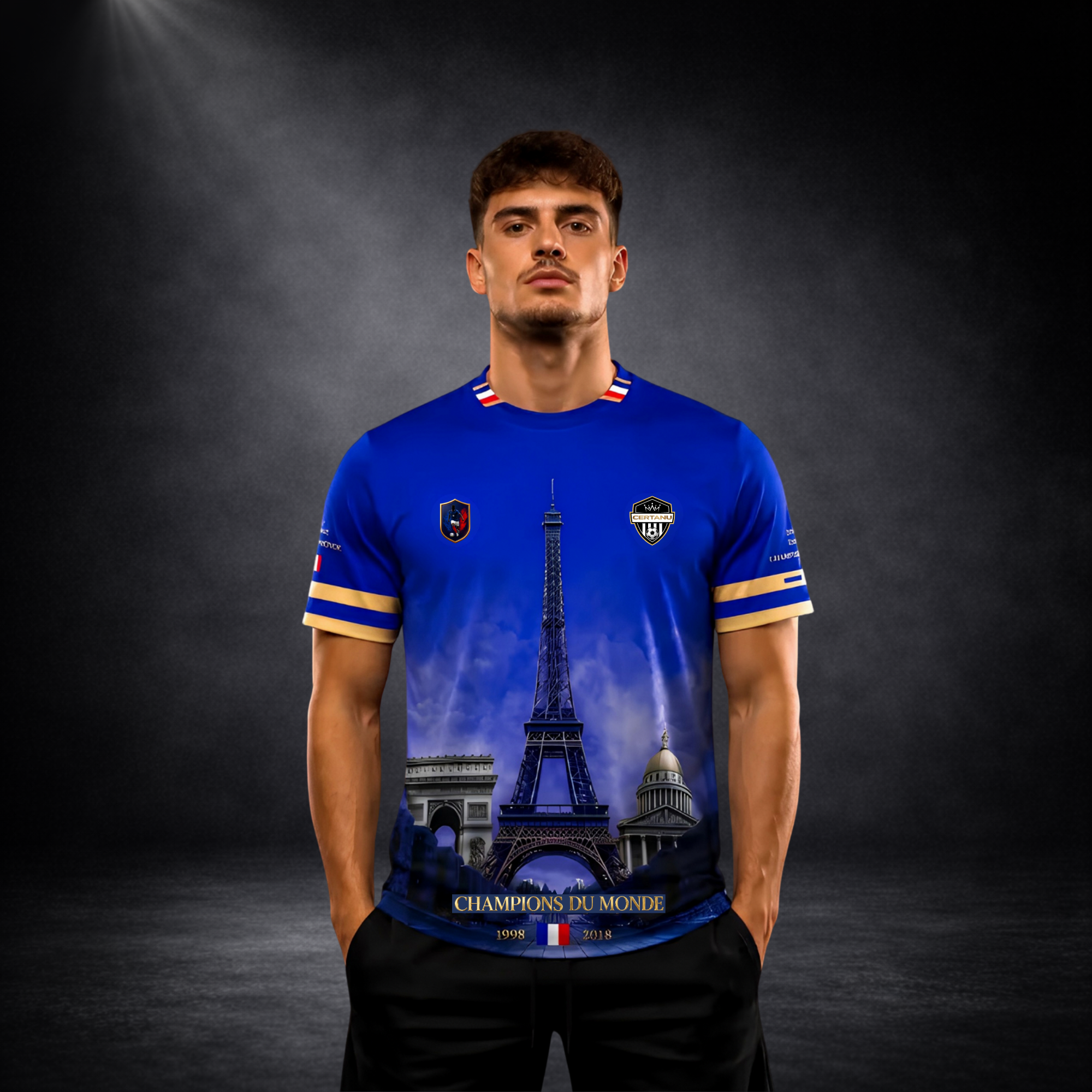 Junger Mann trägt ein blaues CERTANU Frankreich Fan-Shirt vor dunklem Studiohintergrund. Das exklusive Fußball-Design zeigt den Eiffelturm im Zentrum sowie den Arc de Triomphe und das Panthéon als ikonische Wahrzeichen Frankreichs. Auf der Vorderseite befinden sich goldene Akzente, das CERTANU-Wappen und die Aufschrift „Champions du Monde“ mit den Weltmeisterjahren 1998 und 2018. Hochwertiges Lifestyle-Foto für Shopify, Google Shopping und E-Commerce. Premium Frankreich Fan-Shirt für Fußballfans, Nationalma