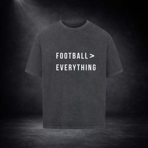 Dunkelgraues Oversized T-Shirt mit weißem Schriftzug „Football > Everything“ auf der Vorderseite, freigestellt vor dunklem Studio-Hintergrund mit Spotlight und dezenter Nebelwirkung
