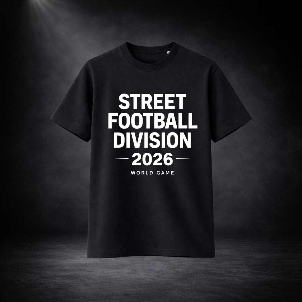 Schwarzes T-Shirt mit weißem Schriftzug „STREET FOOTBALL DIVISION 2026 – WORLD GAME“, freigestellt vor dunklem Studio-Hintergrund mit Spotlight, zentrierte Produktdarstellung