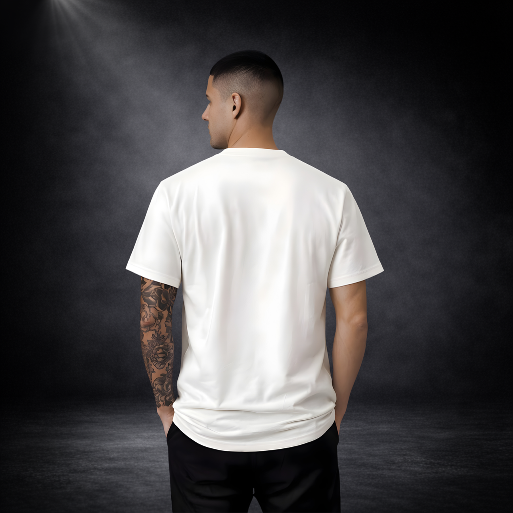 Rückansicht eines jungen Mannes mit tätowiertem Arm in einem weißen T-Shirt ohne Aufdruck, vor dunklem Studio-Hintergrund mit weichem Licht von oben links
