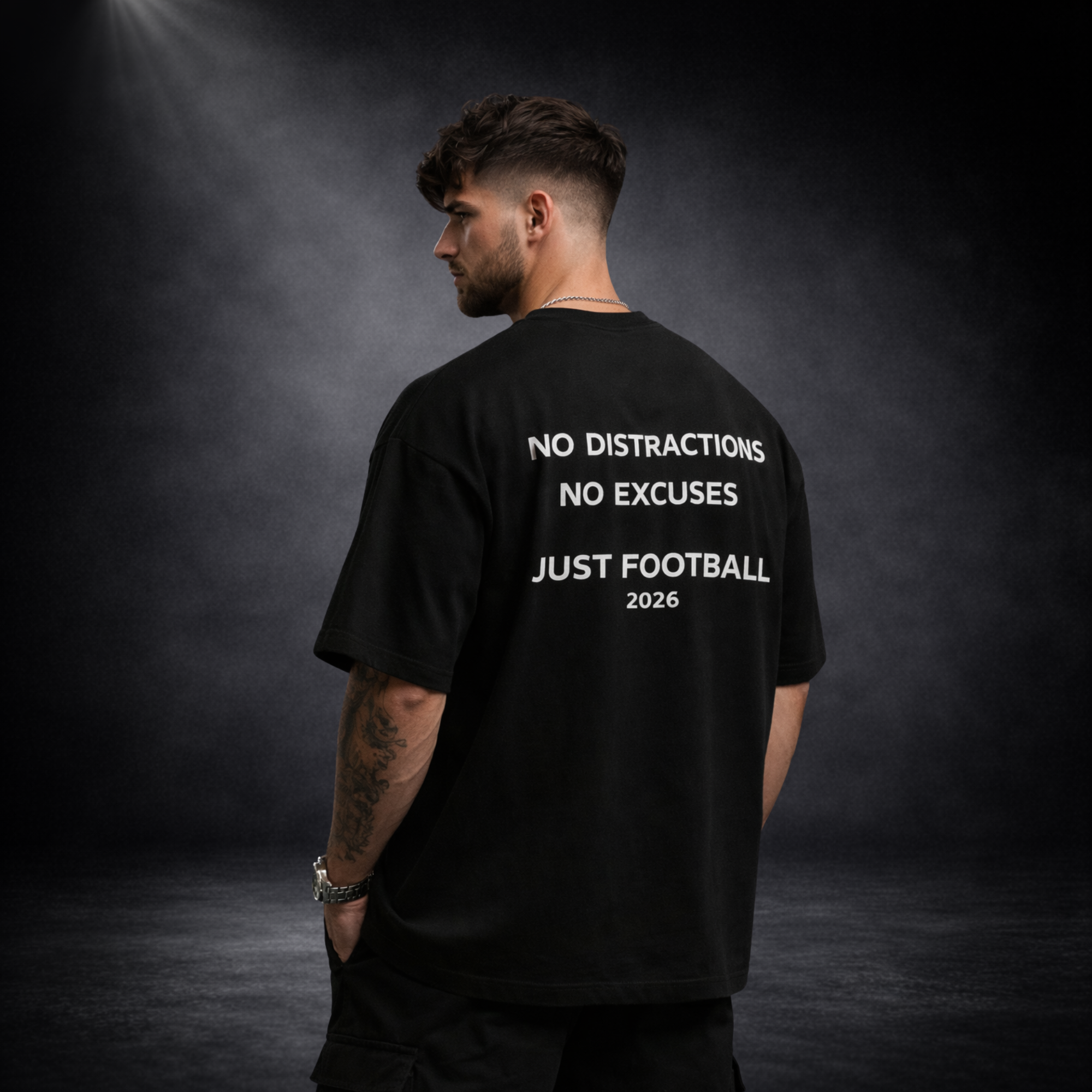Schwarzes Oversized T-Shirt Rückansicht mit großem „No Distractions No Excuses Just Football 2026“ Print, Model auf dunklem Studiohintergrund, Premium Streetwear Design