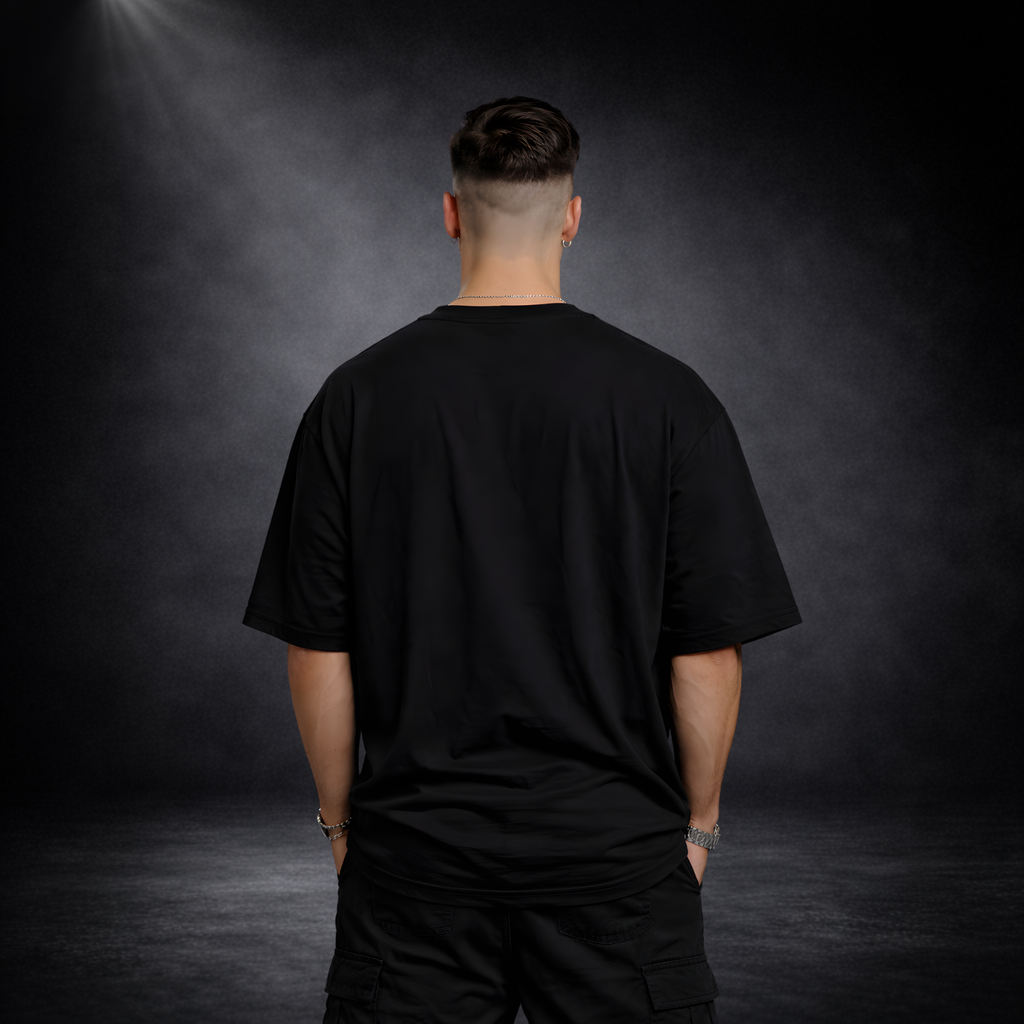 Rückansicht eines männlichen Models mit schwarzem Oversized T-Shirt ohne Print, lockere Passform, minimalistischer Streetwear Look vor dunklem Studio-Hintergrund