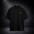 Schwarzes Oversized CERTANU T-Shirt als Freisteller vor einem dunklen Premium-Studiohintergrund mit dezentem Spotlight. Das minimalistische Design zeigt auf der linken Brust ein kleines goldfarbenes CERTANU-Logo mit feinen Akzenten in Schwarz, Rot und Gold. Die lockere Oversized-Passform mit überschnittenen Schultern verleiht dem Shirt einen modernen Streetwear- und Premium-Fashion-Look. Das schlichte Design eignet sich für Fußballfans, Lifestyle-Enthusiasten und Liebhaber hochwertiger Streetwear. Hochwerti