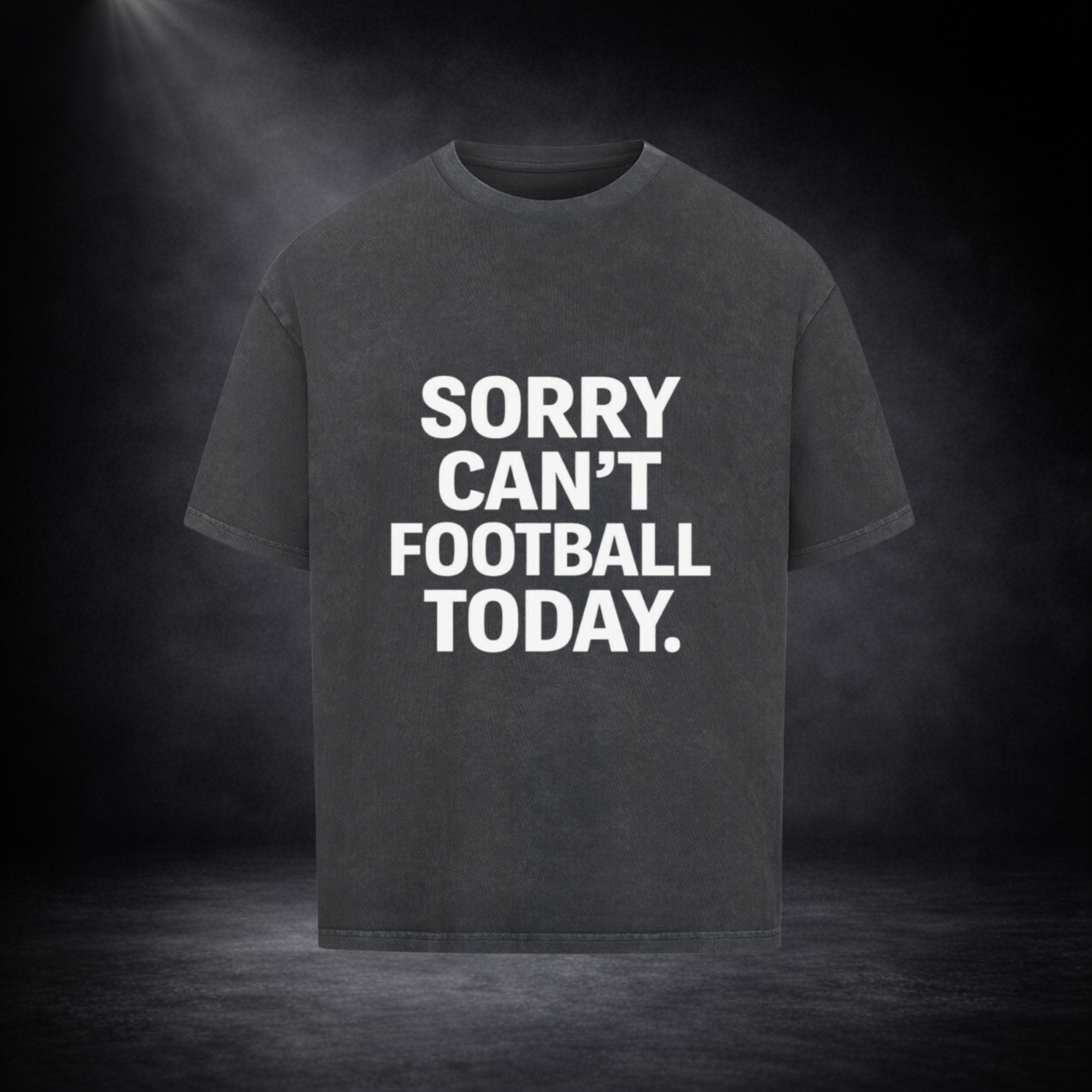 Dunkelgraues Oversized T-Shirt mit großem weißen Schriftzug „SORRY CAN’T FOOTBALL TODAY.“ auf der Vorderseite, inszeniert vor dunklem Studio-Hintergrund mit weichem Lichtspot