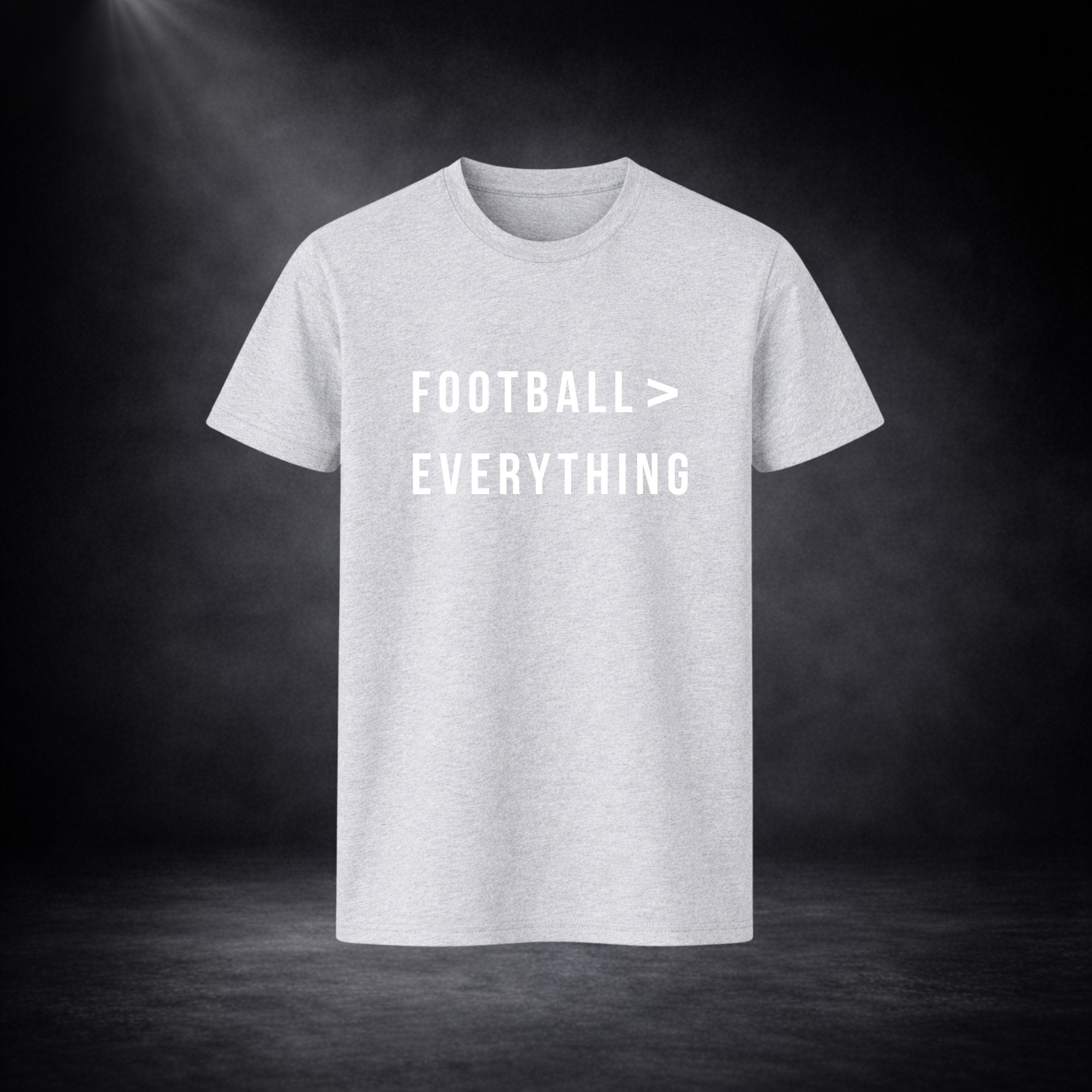 Hellgraues T-Shirt vor dunklem Studio-Hintergrund, frontal dargestellt, mit weißem Schriftzug „FOOTBALL > EVERYTHING“ in schlichter, moderner Typografie