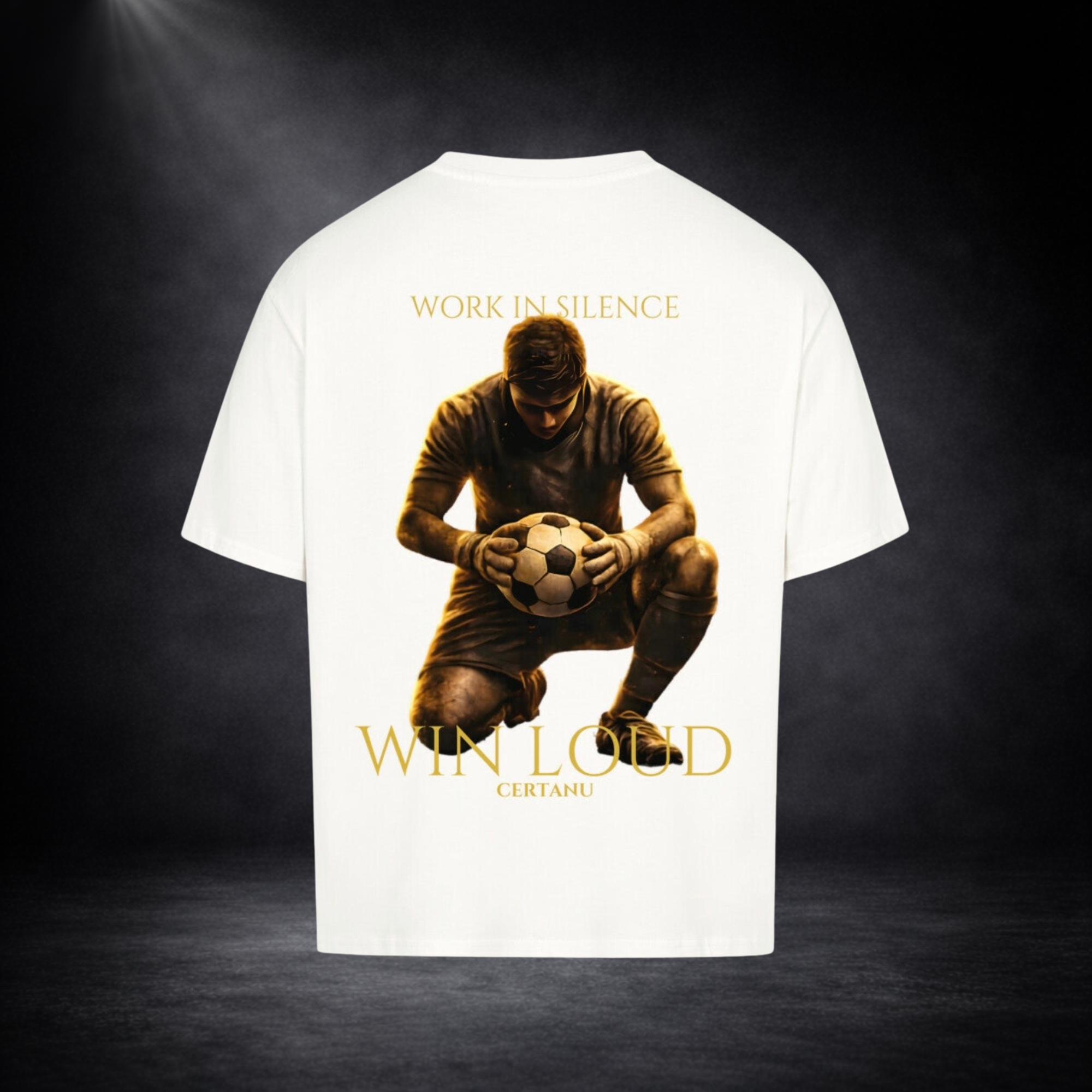 Weises oversized T-Shirt in Rückansicht mit großem goldenem Motiv eines knienden Fußballspielers mit Ball, Schriftzug „WORK IN SILENCE“ oben und „WIN LOUD CERTANU“ unten, vor dunklem Studio-Hintergrund