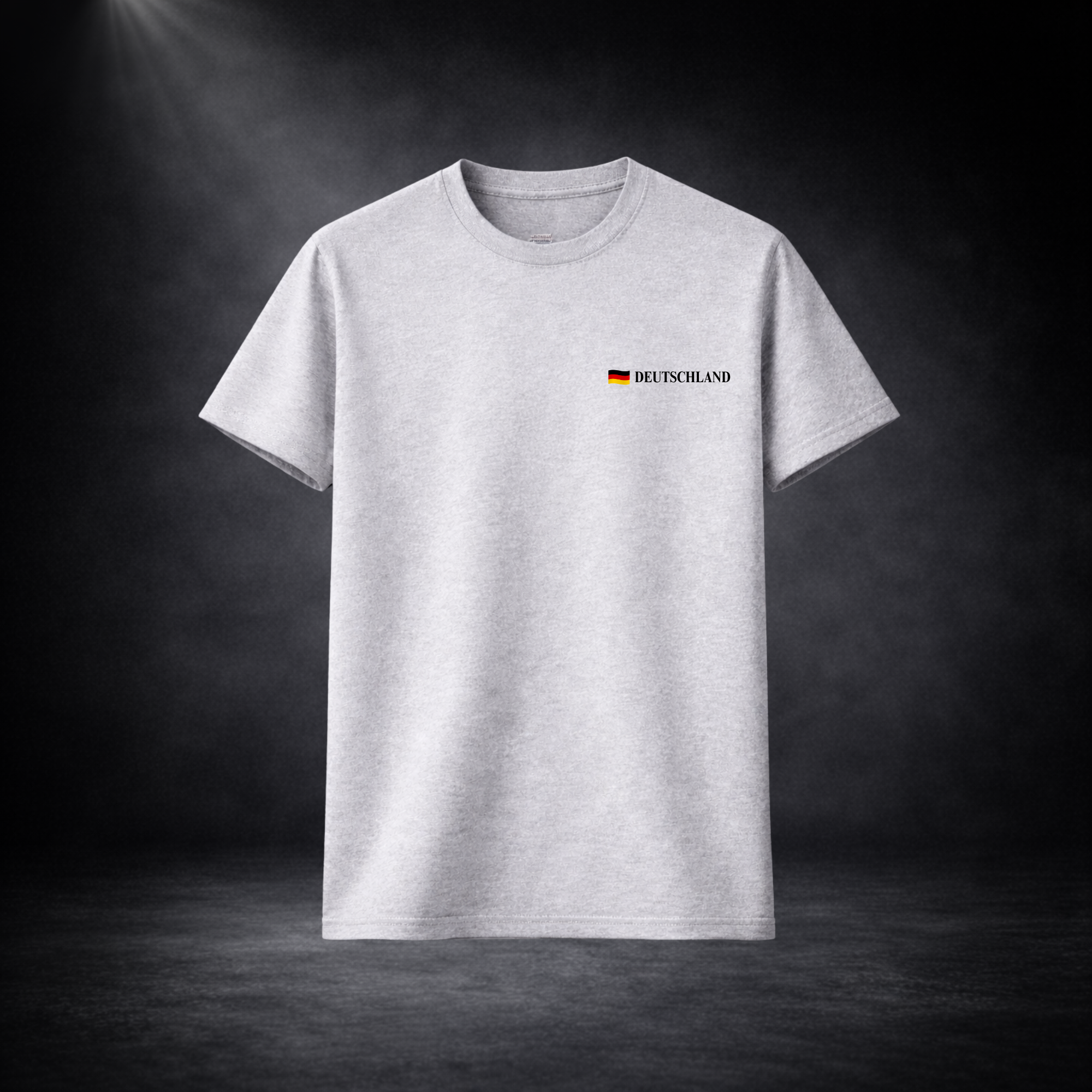 Graues Deutschland T-Shirt mit kleinem Brustlogo und Flagge, minimalistisches Fußball Fan Design für WM 2026, freigestellt vor dunklem Studio Hintergrund