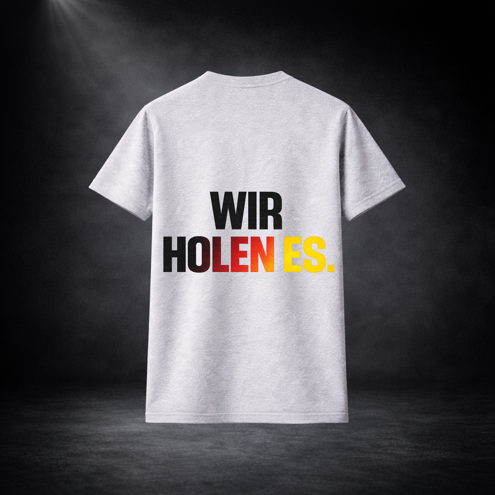 Rückseite eines grauen Deutschland Fan T-Shirts mit großem „WIR HOLEN ES.“ Schriftzug in Schwarz, Rot und Gelb, minimalistisches Fußball WM 2026 Design vor dunklem Studio Hintergrund
