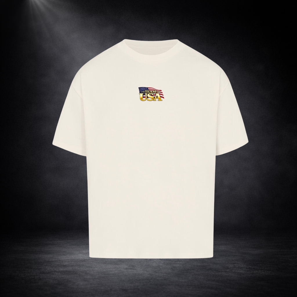 Beiges oversized T-Shirt Vorderseite mit kleinem „Team USA“-Logo auf der Brust, US-Flaggen-Element, dunkler Studio-Hintergrund