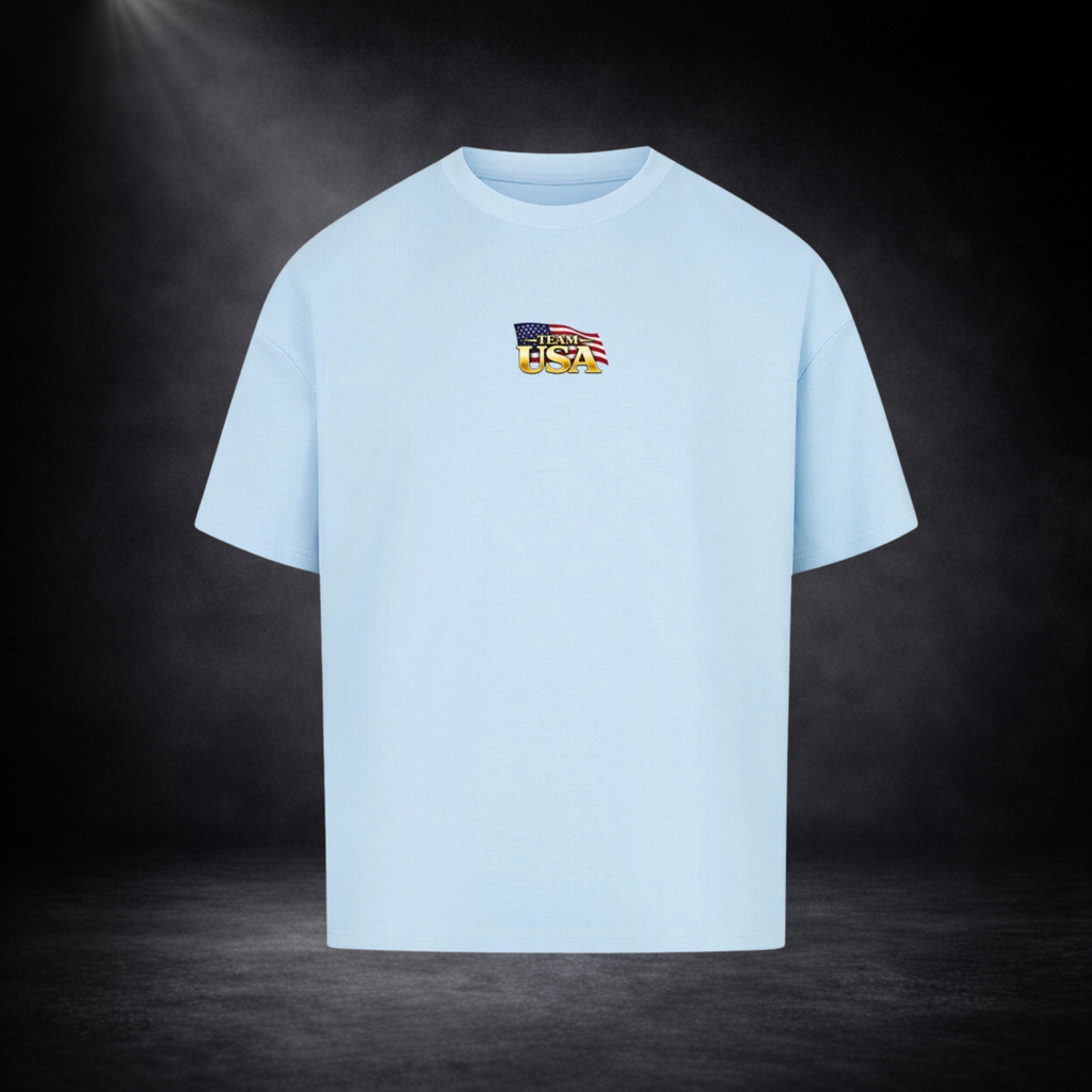Hellblau oversized T-Shirt Vorderseite mit kleinem „Team USA“-Logo auf der Brust, US-Flaggen-Element, dunkler Studio-Hintergrund