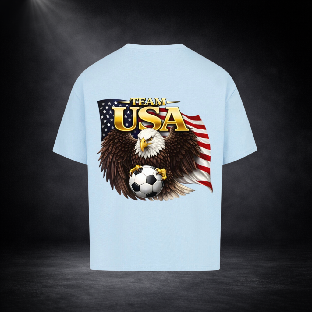 Hellblau oversized T-Shirt Rückseite mit großem „Team USA“-Print, Adler mit Fußball vor US-Flagge, dunkler Studio-Hintergrund