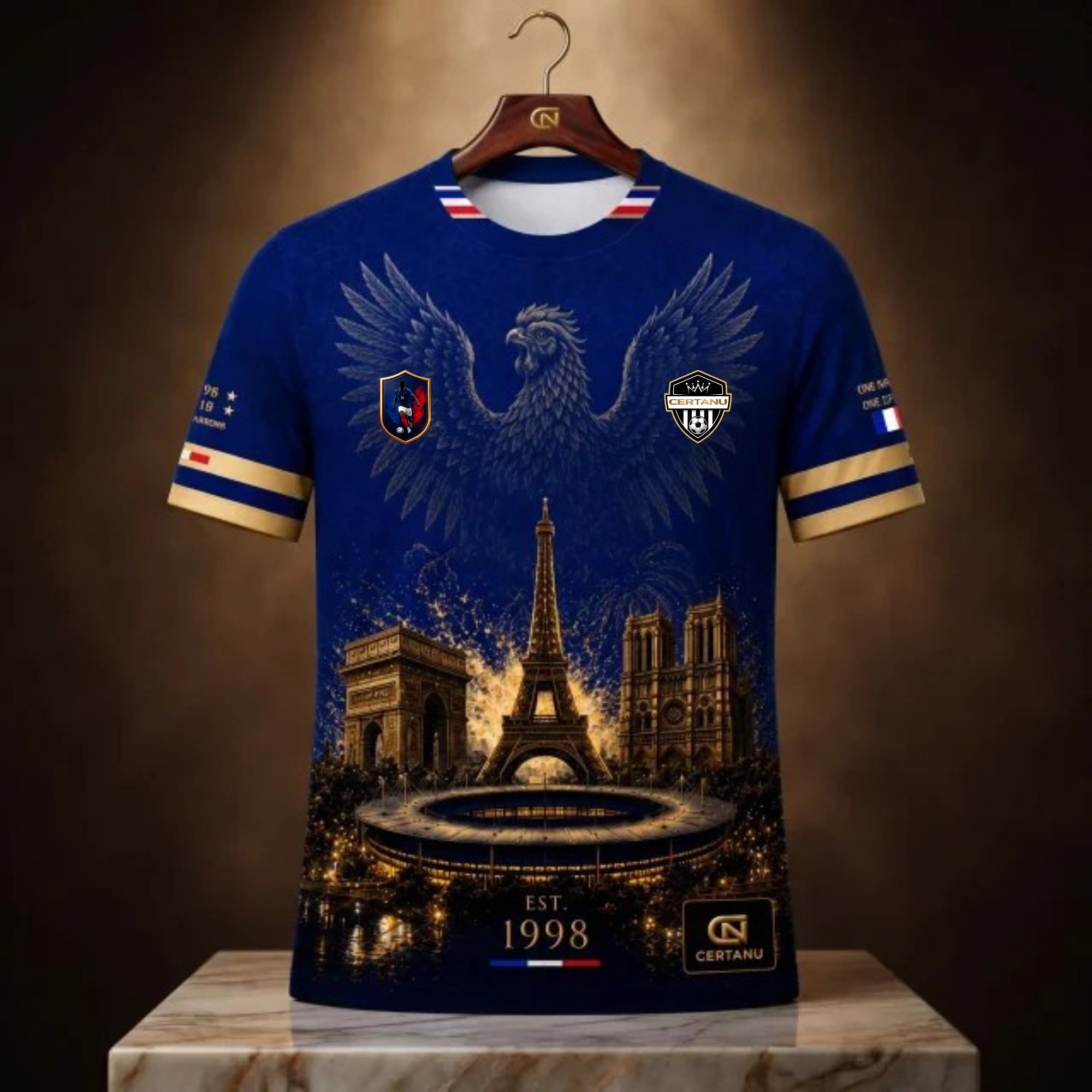 Dunkelblaues CERTANU Frankreich Fußball Fan-Shirt auf einem Holzkleiderbügel präsentiert. Das hochwertige Design zeigt einen großen französischen Hahn über dem Eiffelturm, dem Arc de Triomphe, der Kathedrale Notre-Dame und einem modernen Fußballstadion. Goldene Akzente, französische Flaggenfarben am Kragen und an den Ärmeln sowie die Jahreszahl 1998 als Erinnerung an den Weltmeistertitel Frankreichs verleihen dem Shirt einen luxuriösen Look. Premium Frankreich Fanwear für Fußballfans, WM, EM und Stadionbesu