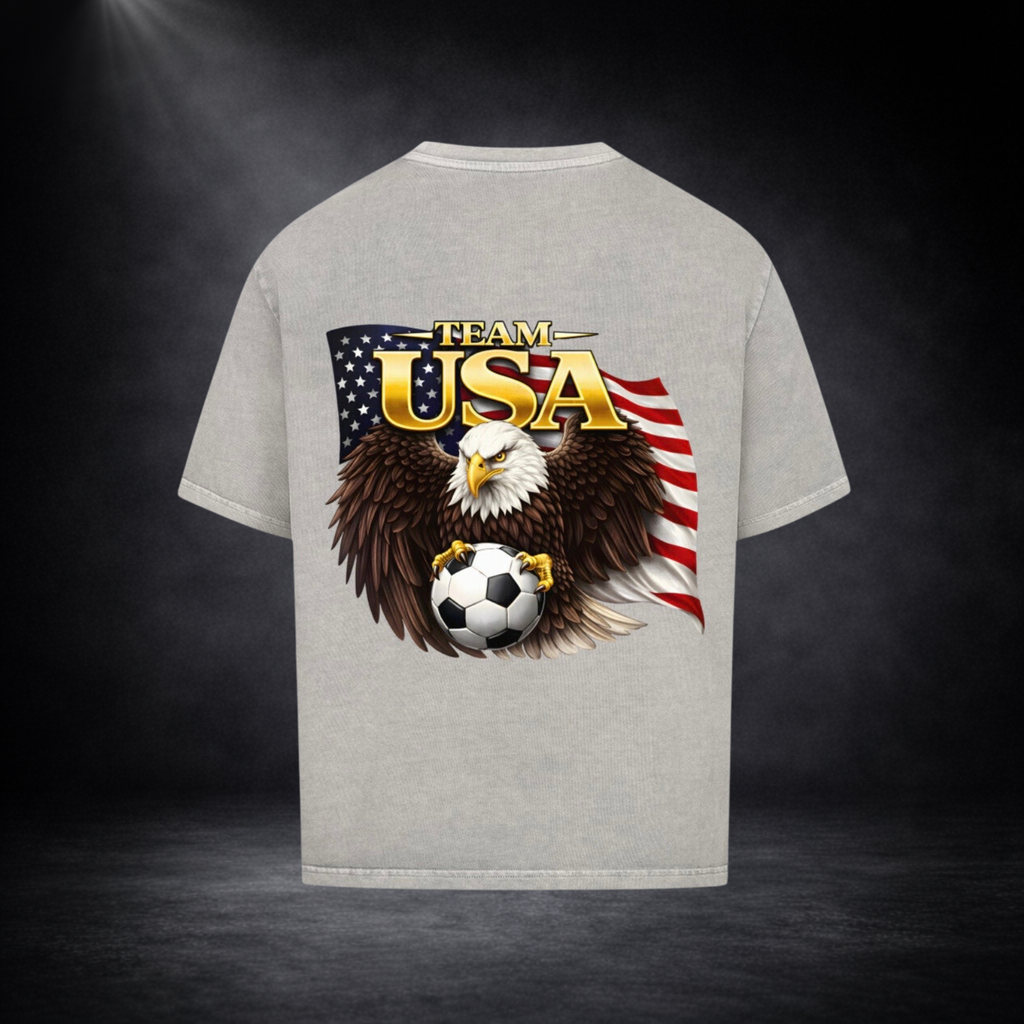 Graue oversized T-Shirt Rückseite mit großem „Team USA“-Print, Adler mit Fußball vor US-Flagge, dunkler Studio-Hintergrund