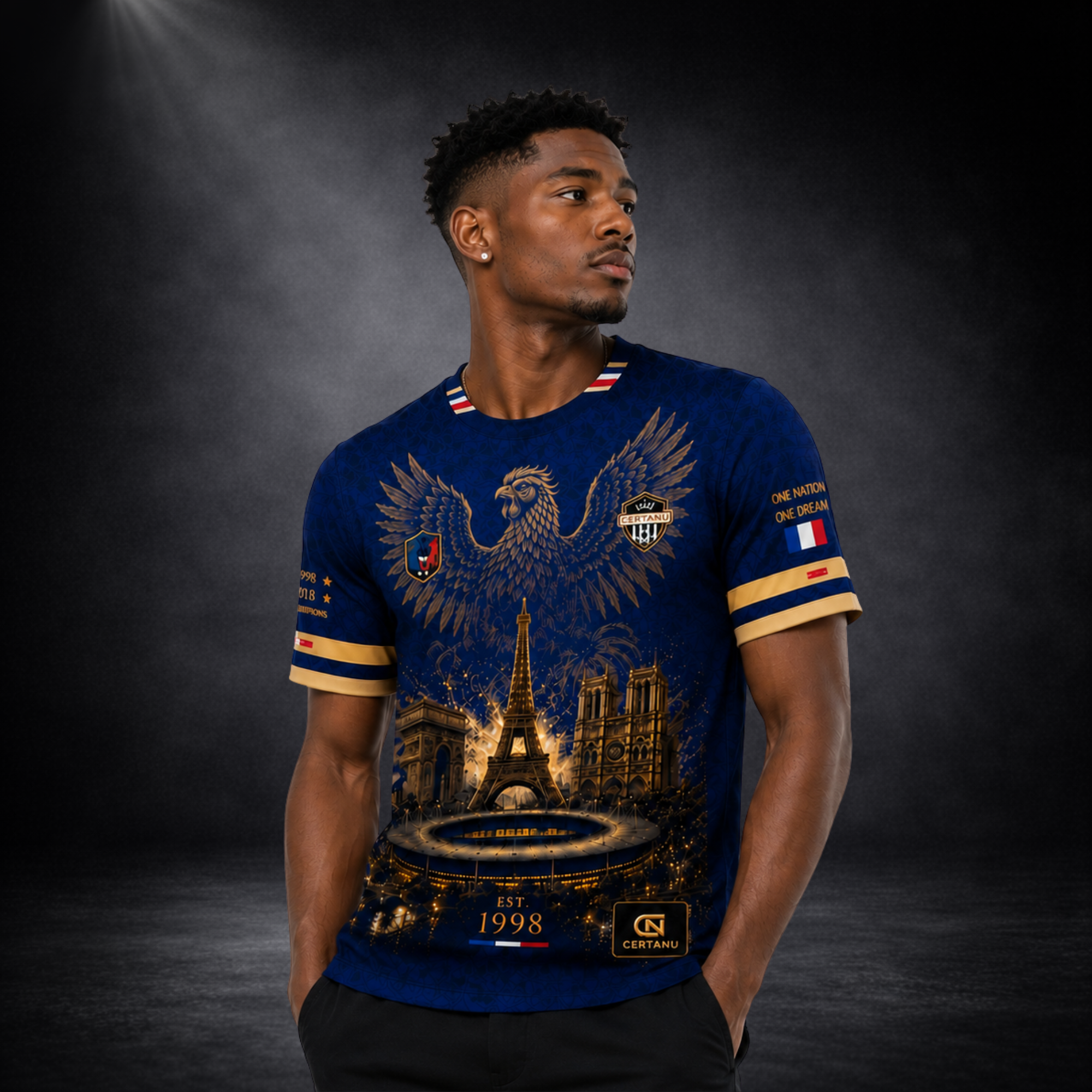 Männliches Model präsentiert ein dunkelblaues CERTANU Frankreich Fußball Fan-Shirt mit luxuriösem Gold-Design. Auf der Vorderseite befinden sich ein großer französischer Hahn, der Eiffelturm, der Arc de Triomphe, die Kathedrale Notre-Dame und ein beleuchtetes Stadion. Französische Flaggen-Details am Kragen und Ärmel sowie die Jahreszahlen 1998 und 2018 symbolisieren die Weltmeistertitel Frankreichs. Hochwertiges Fußball Streetwear-Shirt für Fans der französischen Nationalmannschaft, ideal für WM, EM, Stadio