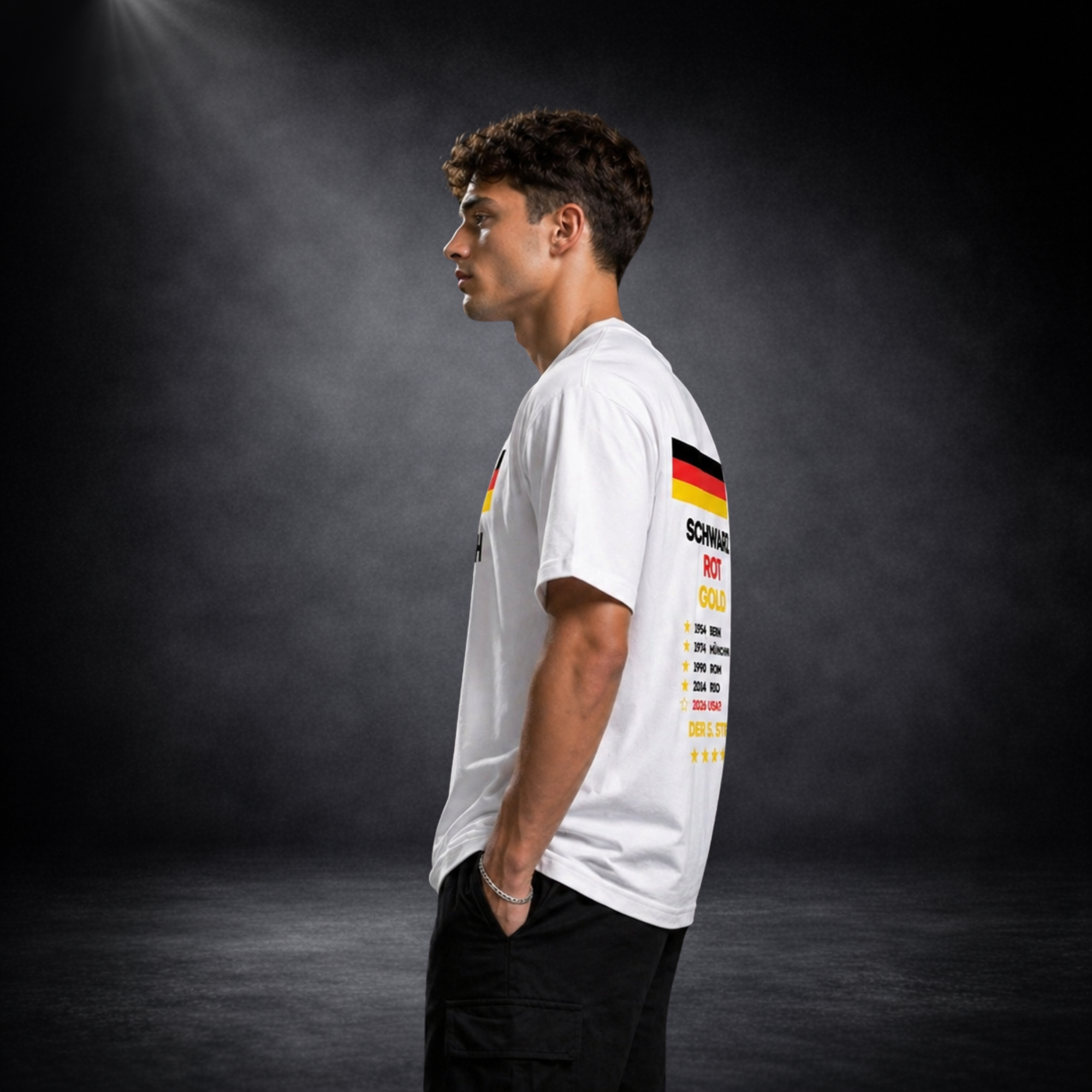 Seitliche Ansicht eines männlichen Models mit weißem Deutschland Fußball T-Shirt, Rückendruck „Schwarz Rot Gold“ mit WM Titeln und Flagge sichtbar, Studioaufnahme mit dunklem Hintergrund