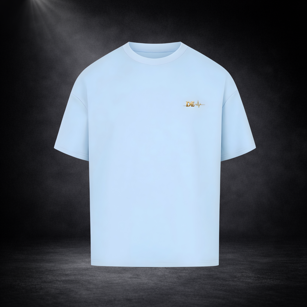 Hellblaues T-Shirt vor dunklem Studio-Hintergrund, minimalistisch dargestellt mit kleinem goldenen Brustlogo, cleanes und modernes Design