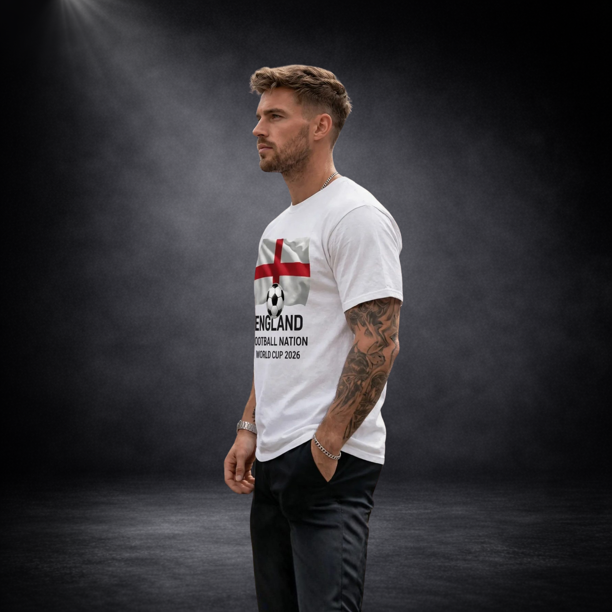 Seitenansicht eines Mannes mit weißem T-Shirt, England-Flaggen- und Fußballmotiv sowie „England Football Nation World Cup 2026“-Aufdruck vor dunklem Studio-Hintergrund