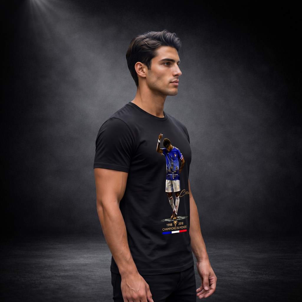 Seitenansicht eines männlichen Models in einem schwarzen CERTANU Premium T-Shirt vor dunklem Studiohintergrund mit weicher Spotlight-Beleuchtung. Das Fußball-Design auf der Vorderseite zeigt einen Spieler im blauen Frankreich-Trikot mit Eiffelturm-Motiv, goldenen CERTANU-Details sowie den Weltmeisterjahren 1998 und 2018. Unter dem Motiv befindet sich der französische Schriftzug „Champions du Monde“ und eine dezente Trikolore in Blau, Weiß und Rot. Das hochwertige Lifestyle-Foto präsentiert die Passform des 