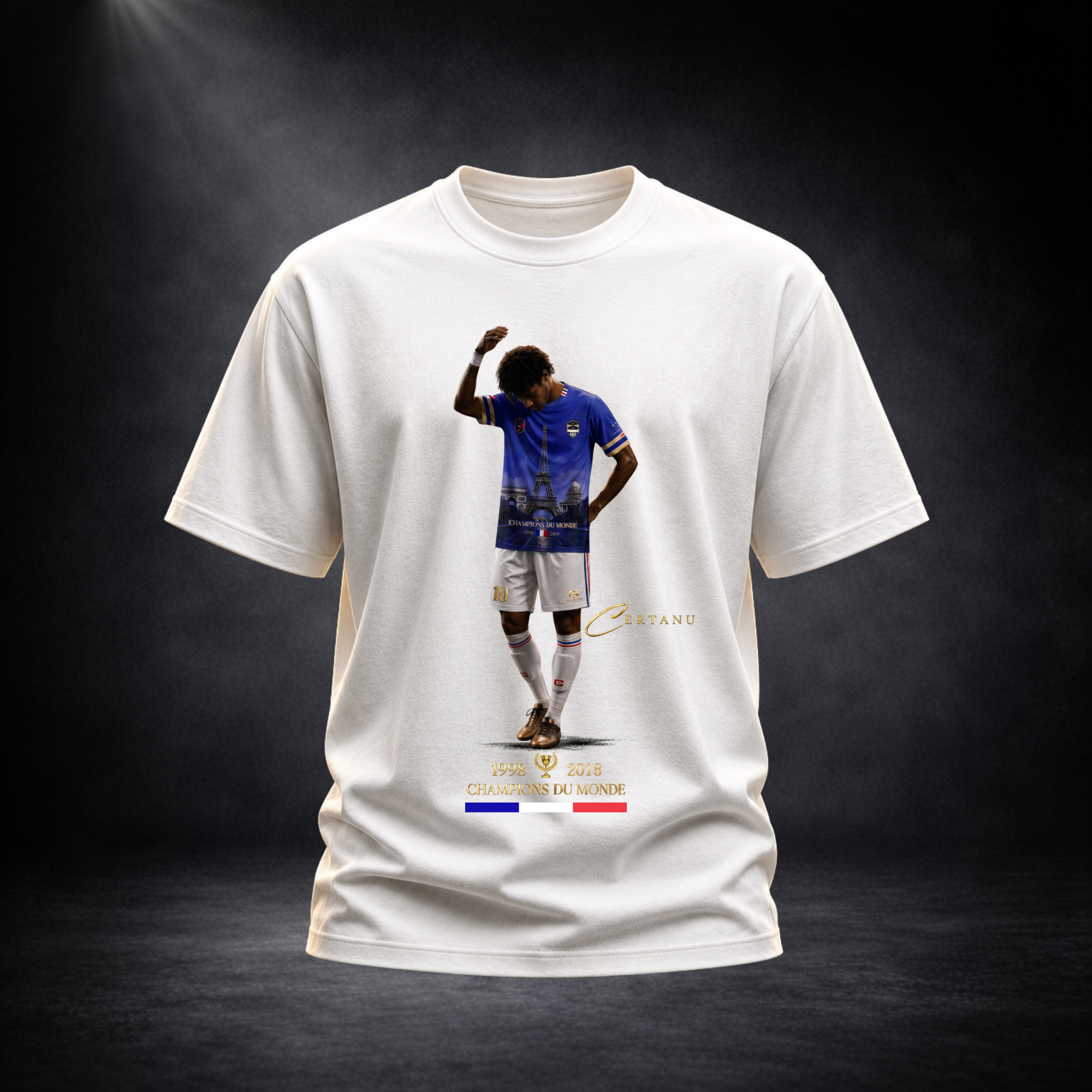 Freigestellte Produktaufnahme eines weißen CERTANU Premium T-Shirts vor dunklem Studiohintergrund mit eleganter Spotlight-Beleuchtung. Das exklusive Frontdesign zeigt einen Fußballspieler im blauen Frankreich-Trikot mit integriertem Eiffelturm-Motiv und goldenen CERTANU-Elementen. Unter dem Motiv befinden sich die Weltmeisterjahre 1998 und 2018, der Schriftzug „Champions du Monde“ sowie die französische Trikolore in Blau, Weiß und Rot. Das hochwertige Fan-Shirt verbindet französische Fußballgeschichte mit m