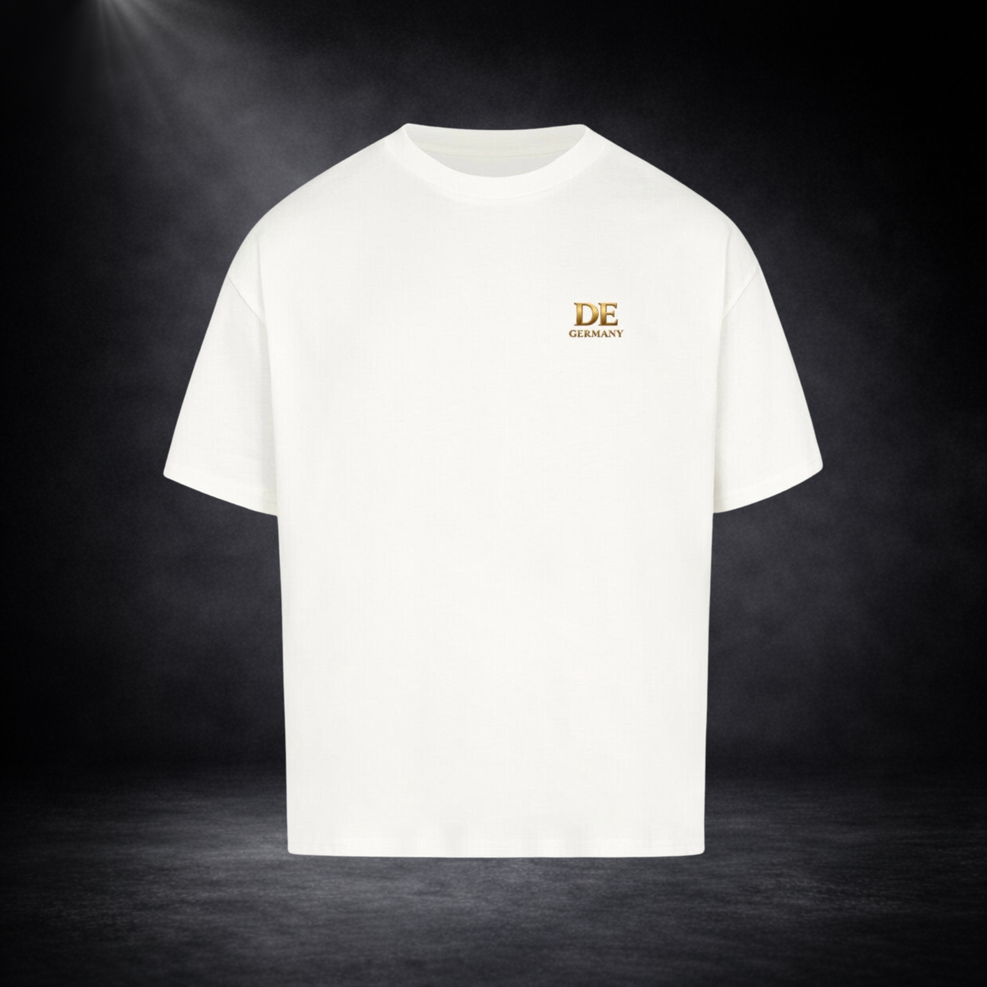 Weißes Oversized T-Shirt mit kleinem goldenen „DE Germany“ Logo auf der Brust, freigestellt vor dunklem Studio-Hintergrund im minimalistischen Premium-Look