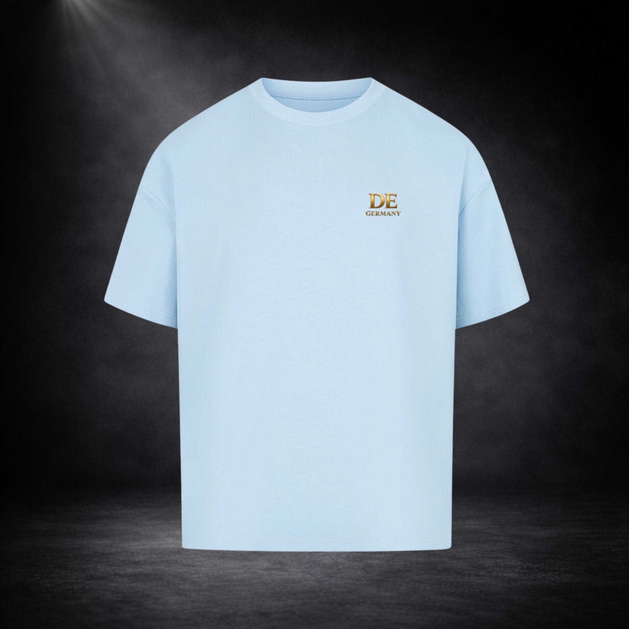 Hellblaues Oversized T-Shirt mit kleinem goldenen „DE Germany“ Logo auf der Brust, freigestellt vor dunklem Studio-Hintergrund im cleanen Premium-Look