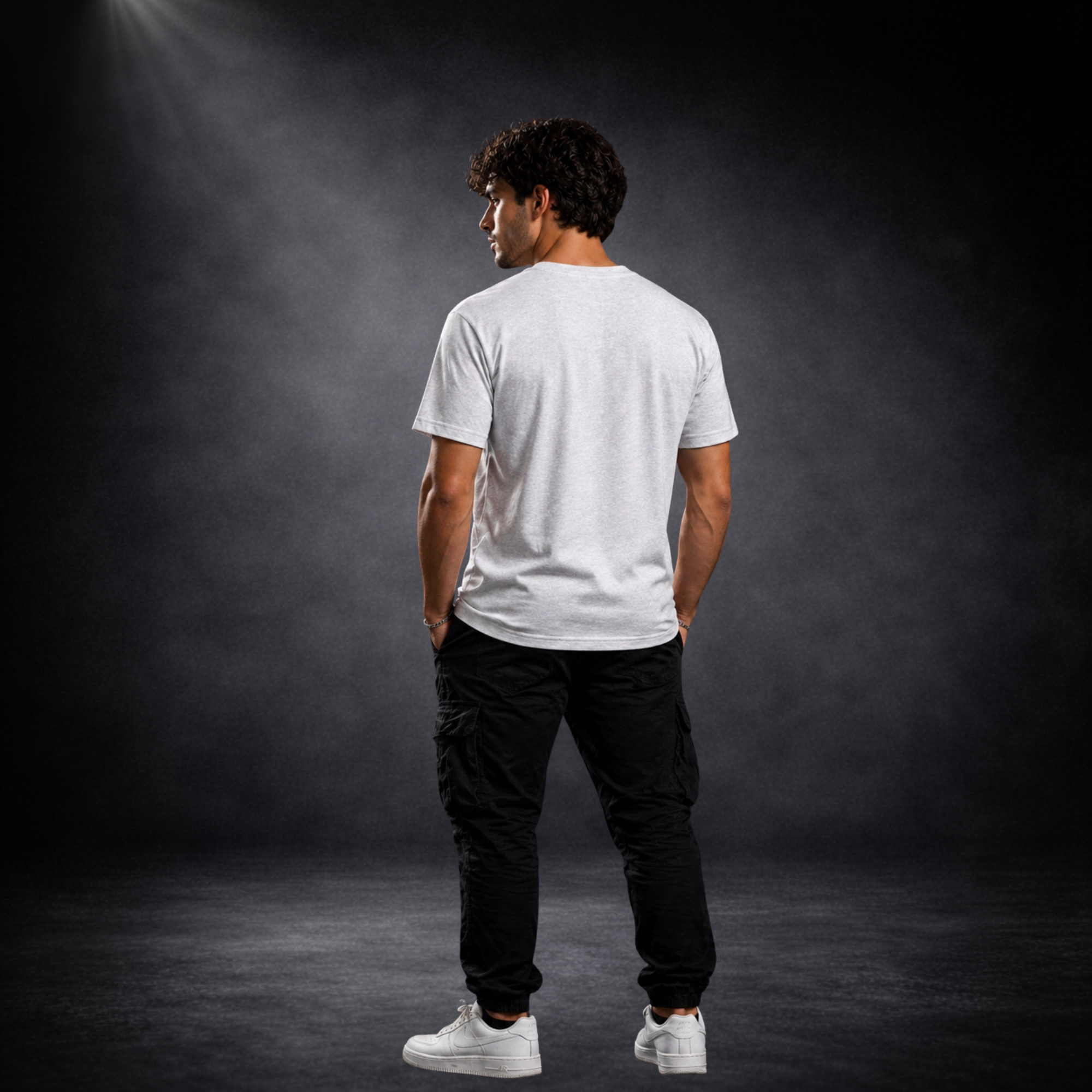 Rückansicht eines jungen Mannes im grauen Basic T-Shirt ohne Print, kombiniert mit schwarzer Hose und weißen Sneakern, minimalistischer Streetwear Look vor dunklem Studiohintergrund