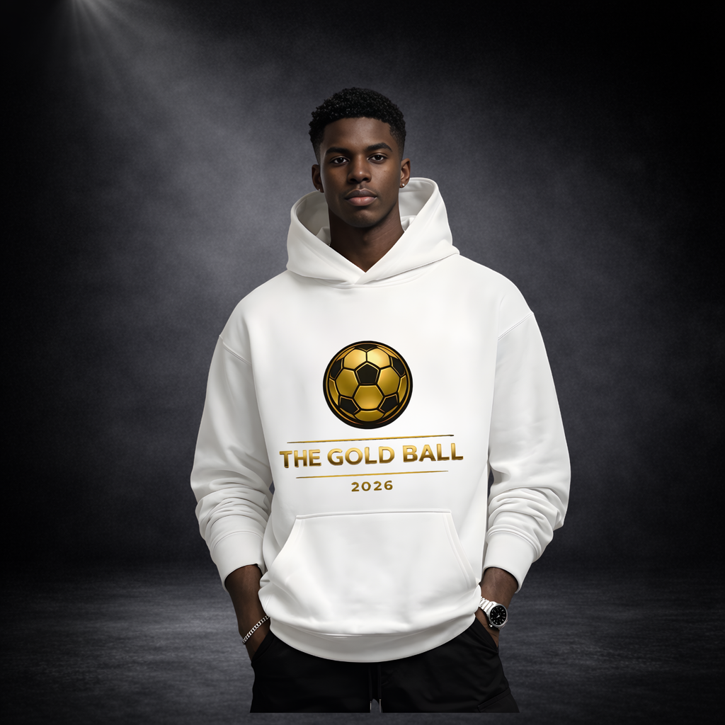 Junger Mann trägt einen weißen Hoodie mit goldenem Fußball-Logo und Schriftzug „THE GOLD BALL 2026“, Hände in den Taschen, vor dunklem Studio-Hintergrund mit Spotlight