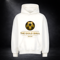 Weißer Hoodie mit goldfarbenem Fußball-Logo und Schriftzug „THE GOLD BALL 2026“, mittig platziert, vor dunklem Studio-Hintergrund mit Spotlight