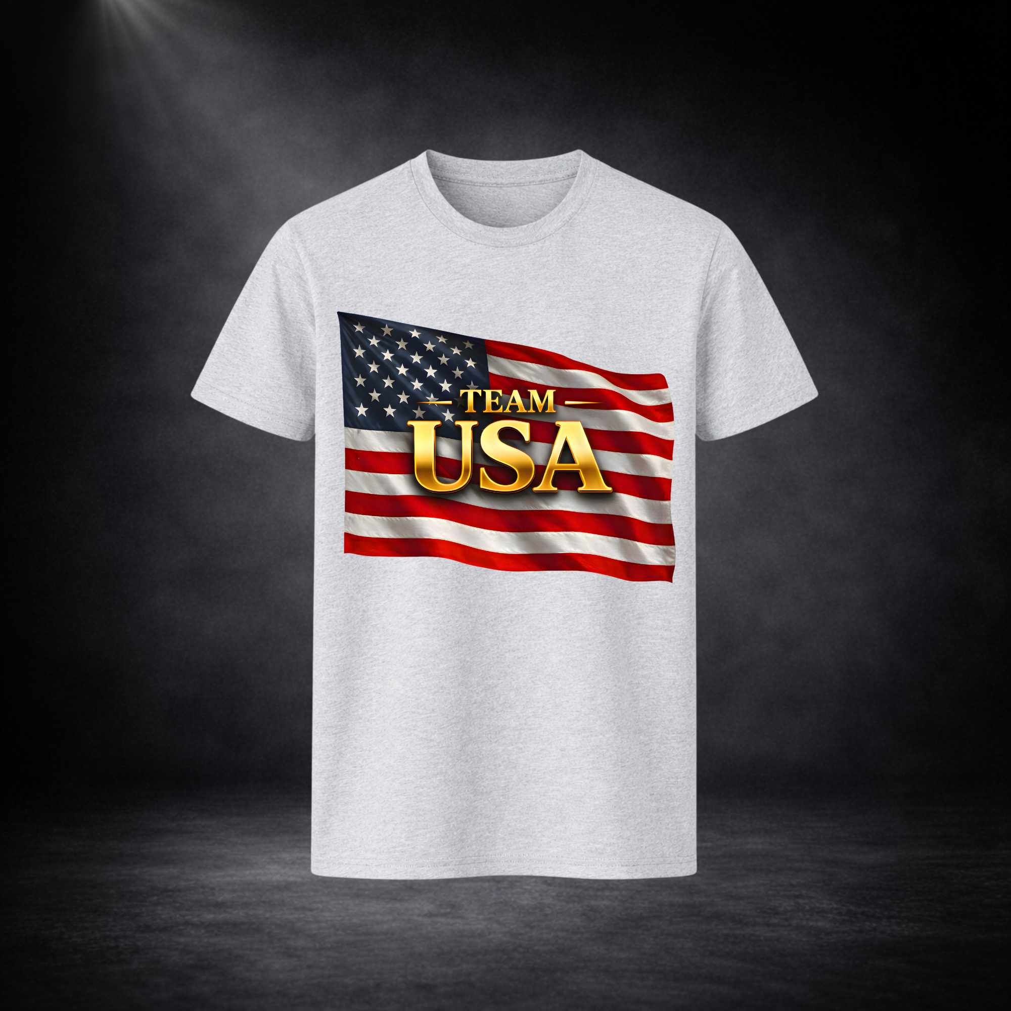 Hellgraues T-Shirt mit „TEAM USA“-Aufdruck in Gold vor amerikanischer Flagge, freigestellt vor dunklem Studio-Hintergrund