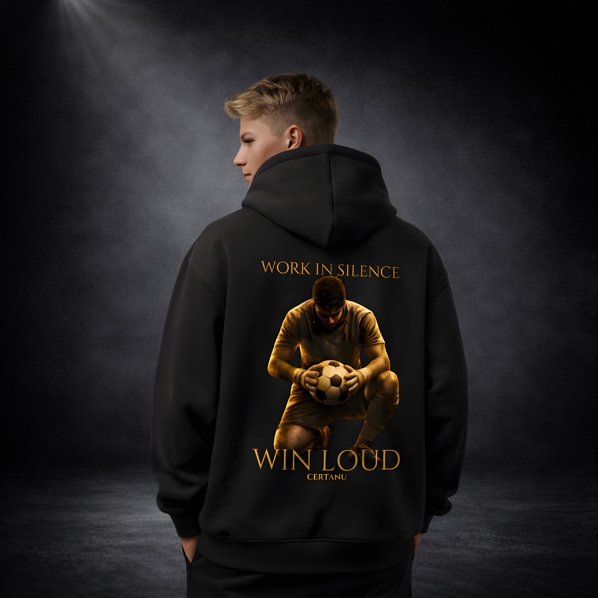 Person trägt schwarzen CERTANU Hoodie von hinten mit großem Rückenprint „Work in Silence Win Loud“ und Fußballmotiv, vor dunklem Studio-Hintergrund